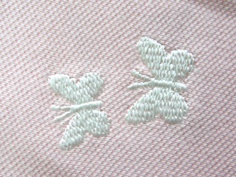 Detail výšivky motýlků na kojenckém triku s krátkým rukávem